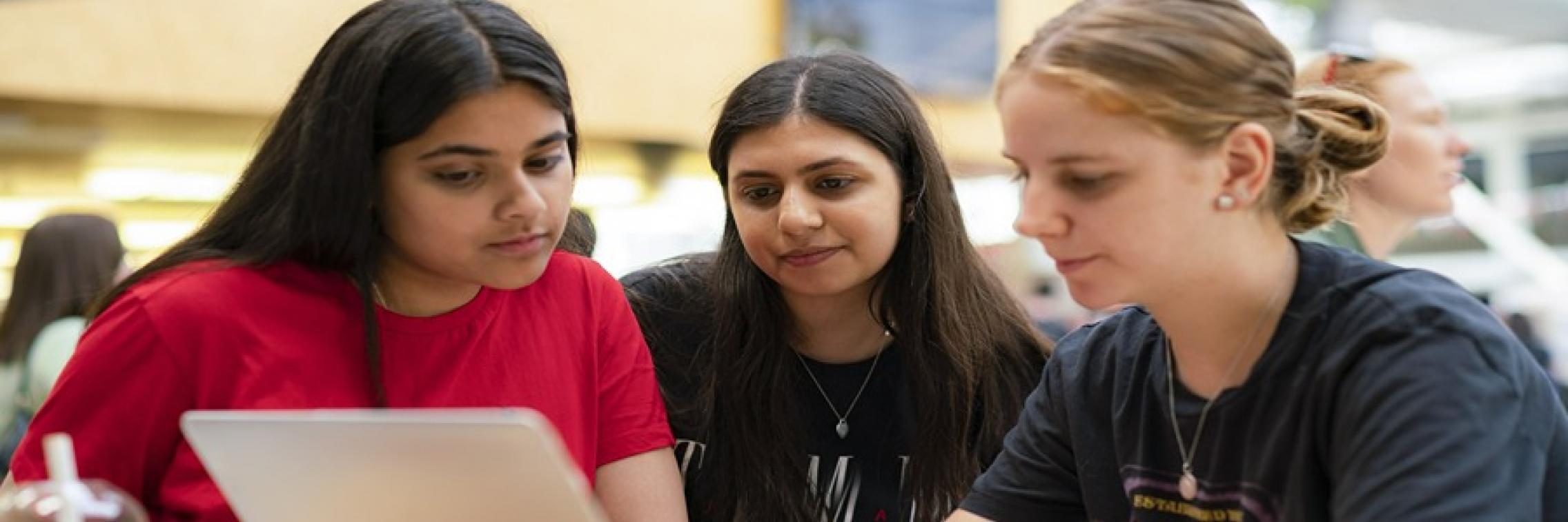 young women studying together at laptop