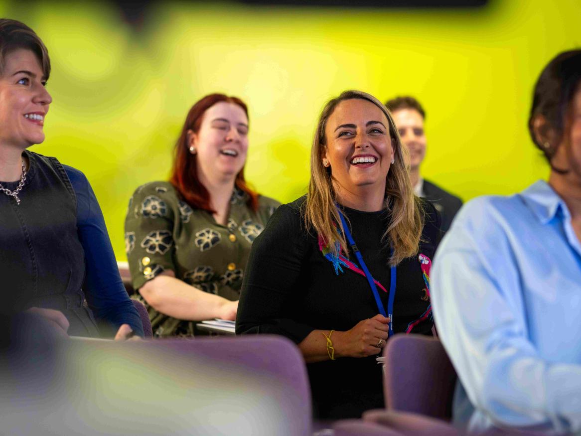 a room of professionals sitting theatre style smiling